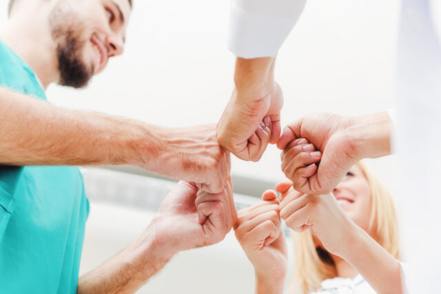 Doctor, surgeon and nurse join hands together.