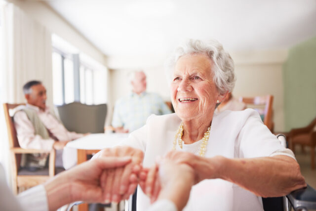 Nurse’s hands hold elderly woman’s at nursing home