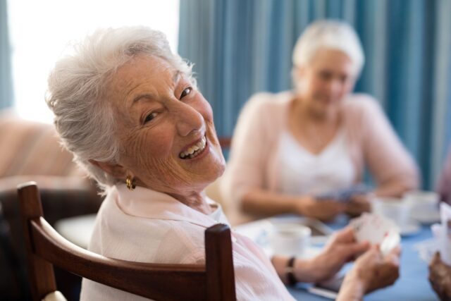 Smiling senior woman playing cards with friends